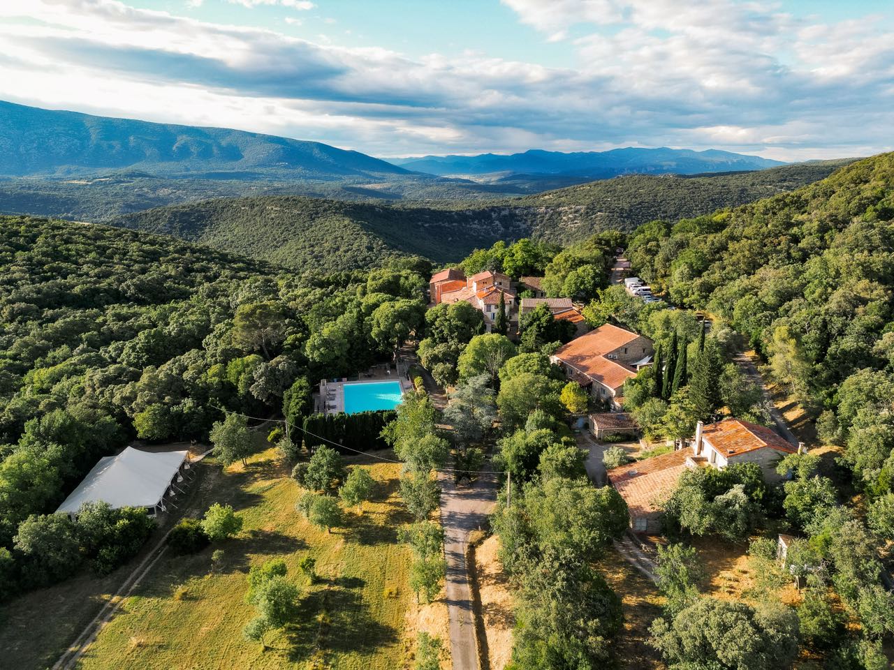 Vue aérienne du Hameau de l’Étoile, ses bâtiments de pierre et sa piscine au milieu de la garrigue